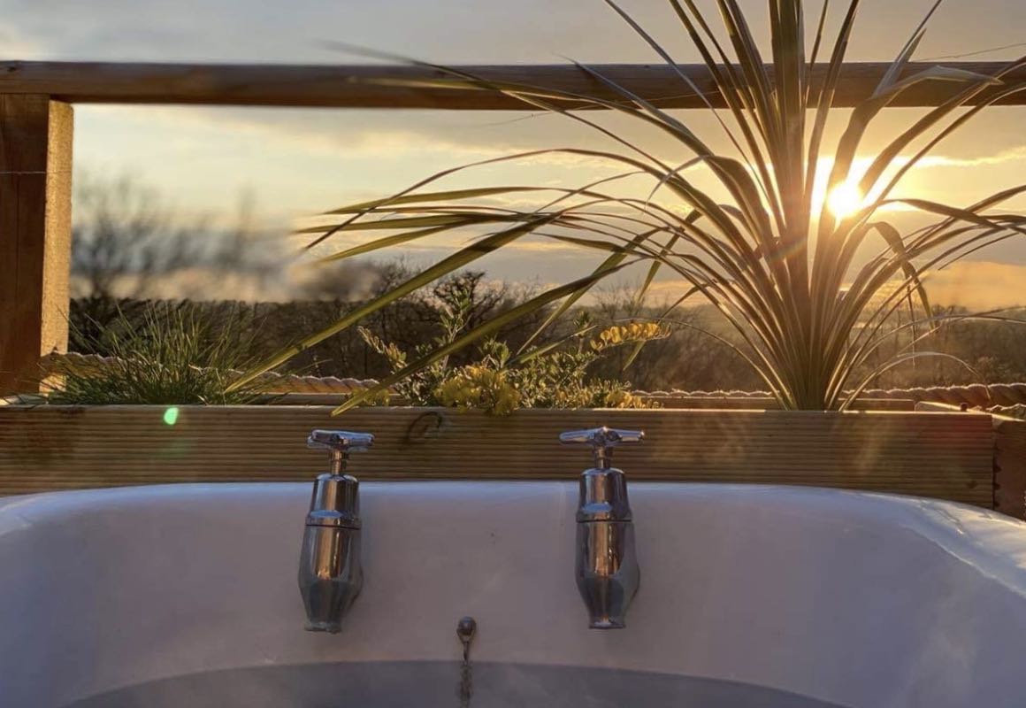 enjoying the sunset in an outdoor bath on the deck of luxury cabin in Devon